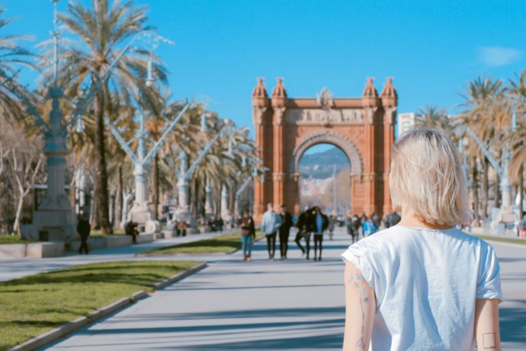 The back of a student traveler taking a tour of the Arc de Triomf in Barcelona, Spain.
