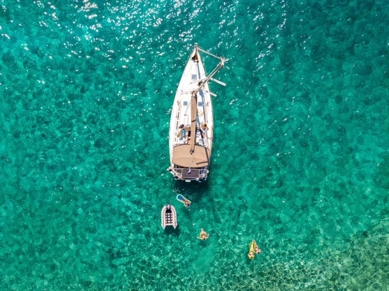 Student travelers on floaties beside a boat on the brilliant blue ocean on this tour.