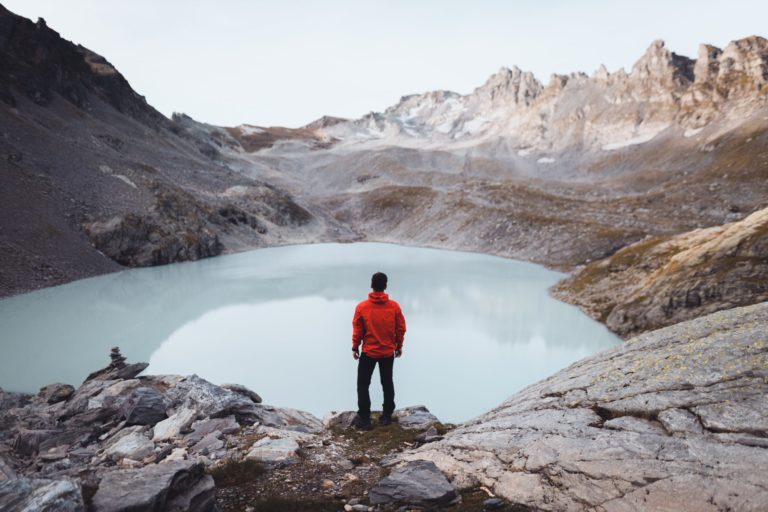 A student traveler overlooking a lake with snow-capped mountains in Switzerland.