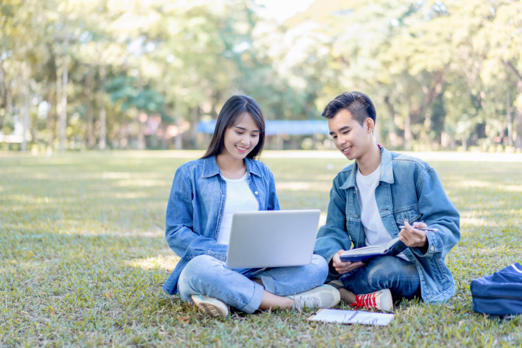 A young female college student and male university student sit in a park studying with their laptop and textbooks. Students Fare can help plan a study abroad trip for students everywhere.