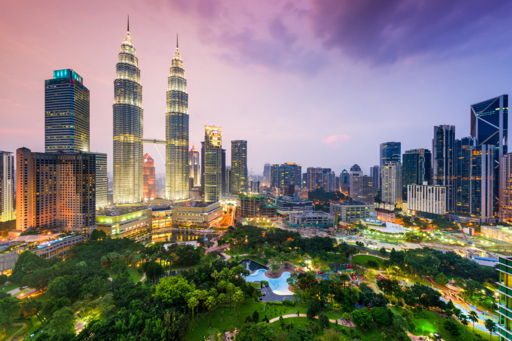 The Kuala Lumpur city skyline near Kuantan in Malaysia, which features the twin towers and a beautiful park. This image is featured in the Students Fare student travel blog, "Best Destinations for Solo Travelers," which lists places for individual tours.