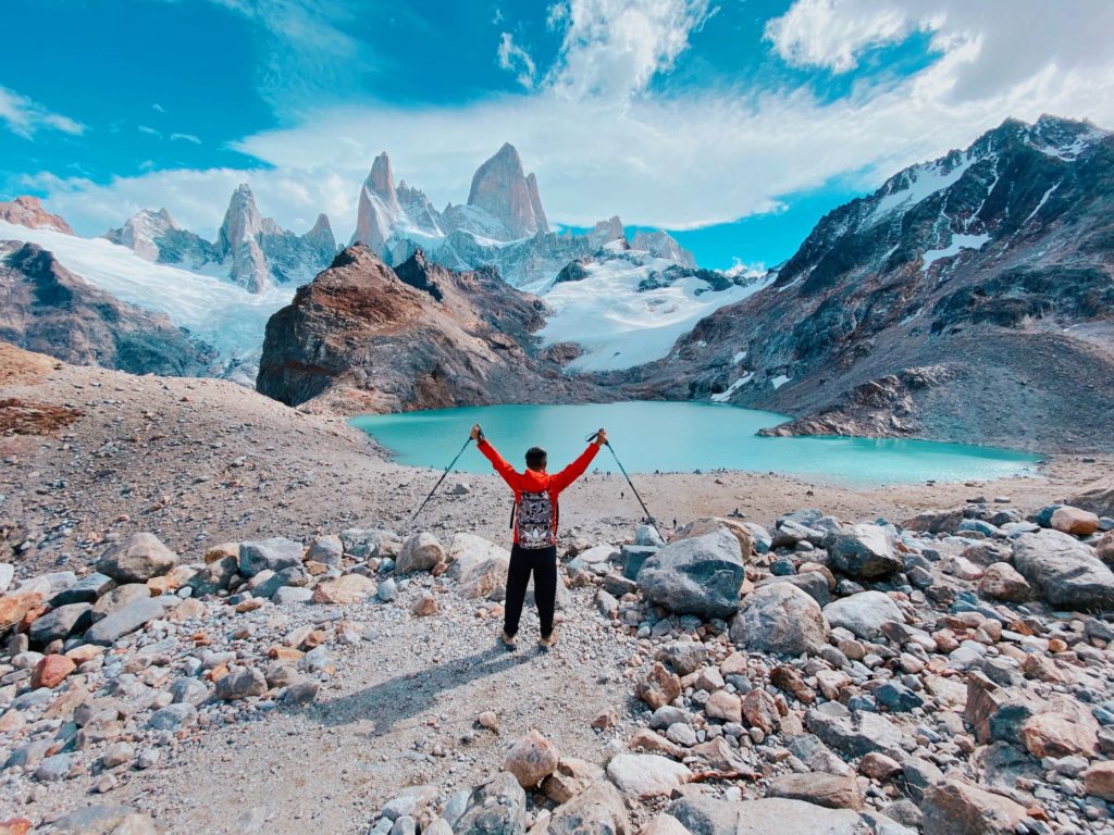 A young man in hiking gear posts in front of a beautiful Patagonia, Argentina, Chile after hiking the mountains on a solo vacation. This image is featured in the Students Fare student travel blog, "Best Destinations for Solo Travelers," which lists places for individual tours.