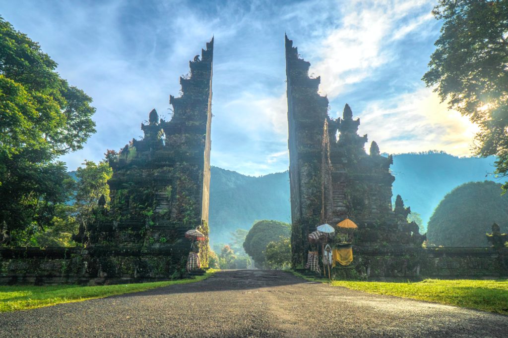A beautiful ancient stone gate of Ubud, Bali, Indonesia, surrounded by the iconic green lush mountains. This image is featured in the Students Fare student travel blog, "Best Destinations for Solo Travelers," which lists places for individual tours.