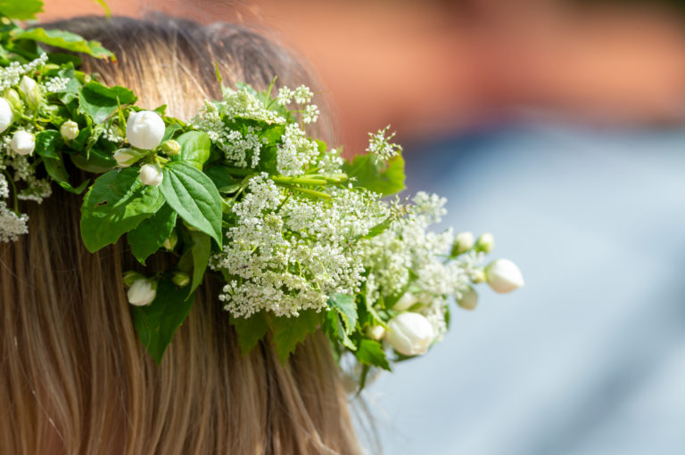 A closeup image of a blonde Swedish girl wearing a traditional white and green flower crown. This image is used in the Students Fare student travel blog, "Midsummer in Sweden," which describes the traditional festival and how to celebrate it.