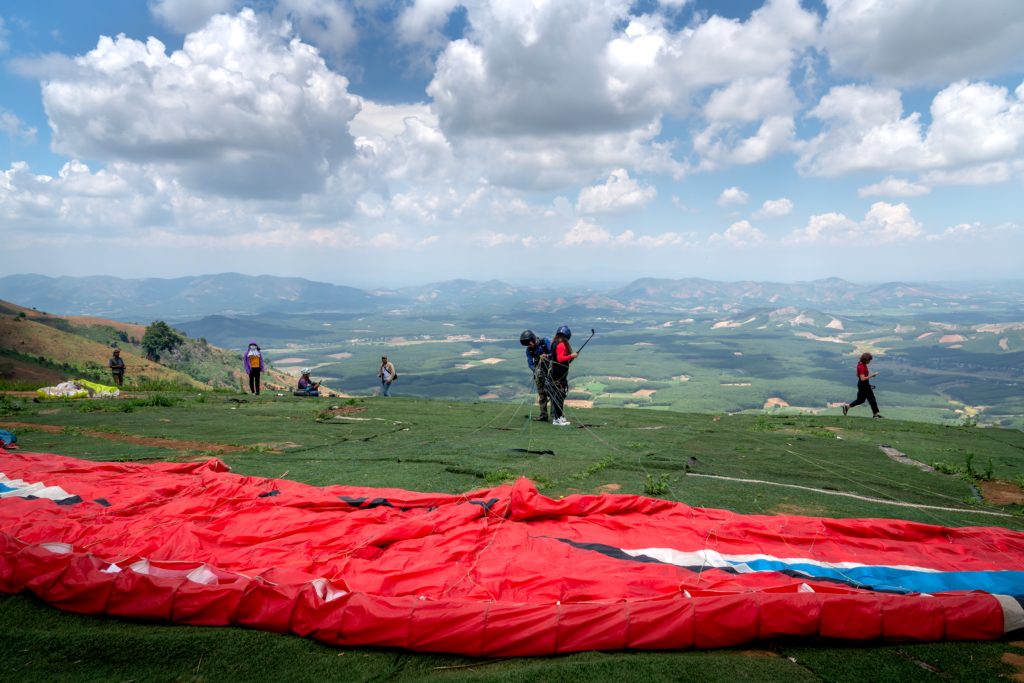 A group of paragliders ending their paragliding tour on top of a mountain and unstrapping the harness and parachute. This image is used in the Students Fare student travel blog, "Best Paragliding Destinations," which is a travel guide for paragliding all around the world.