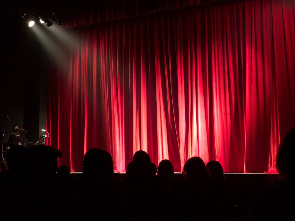 This image of a red curtain pulled closed to hide a auditorium is featured in the Students Fare travel blog, "Fundraising Ideas for Students," which describes different fundraisers for students and faculty to fund study abroad programs and school trips.
