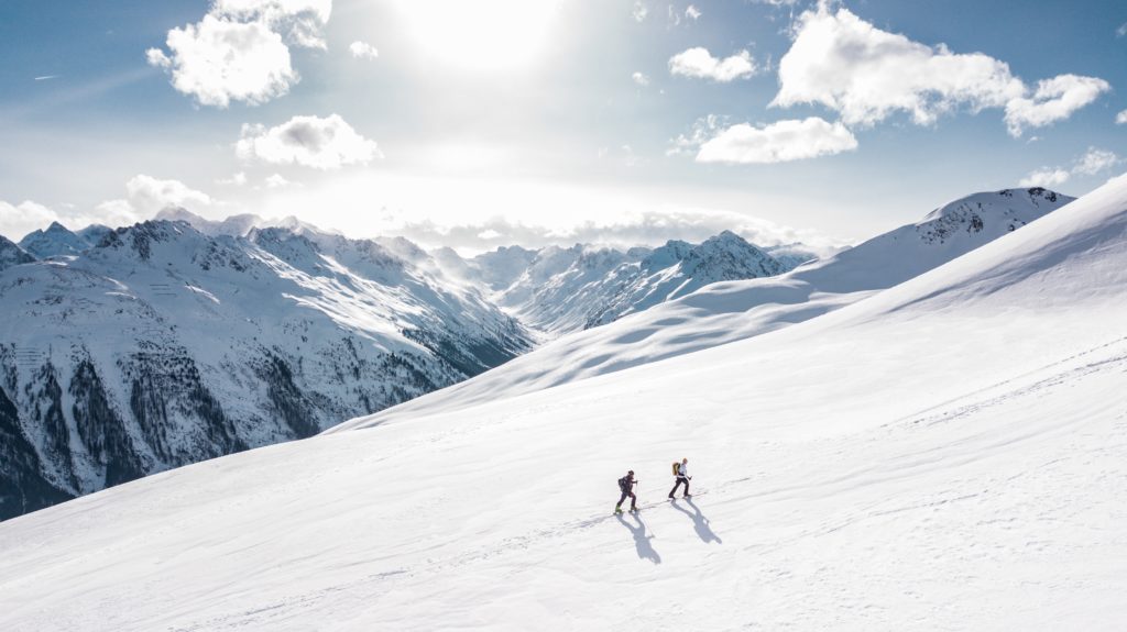 Featured in Backpacking Guide for Students, this image shows two people hiking through snow on a mountain.