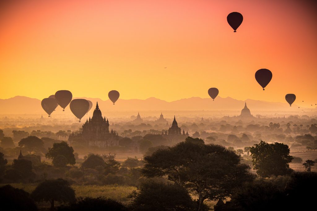 This image of hot air balloons floating over ancient temples and pagoda ruins with a sunset background is featured in "Best Spots for Ballooning," a travel blog article from Students Fare about tours and activities.