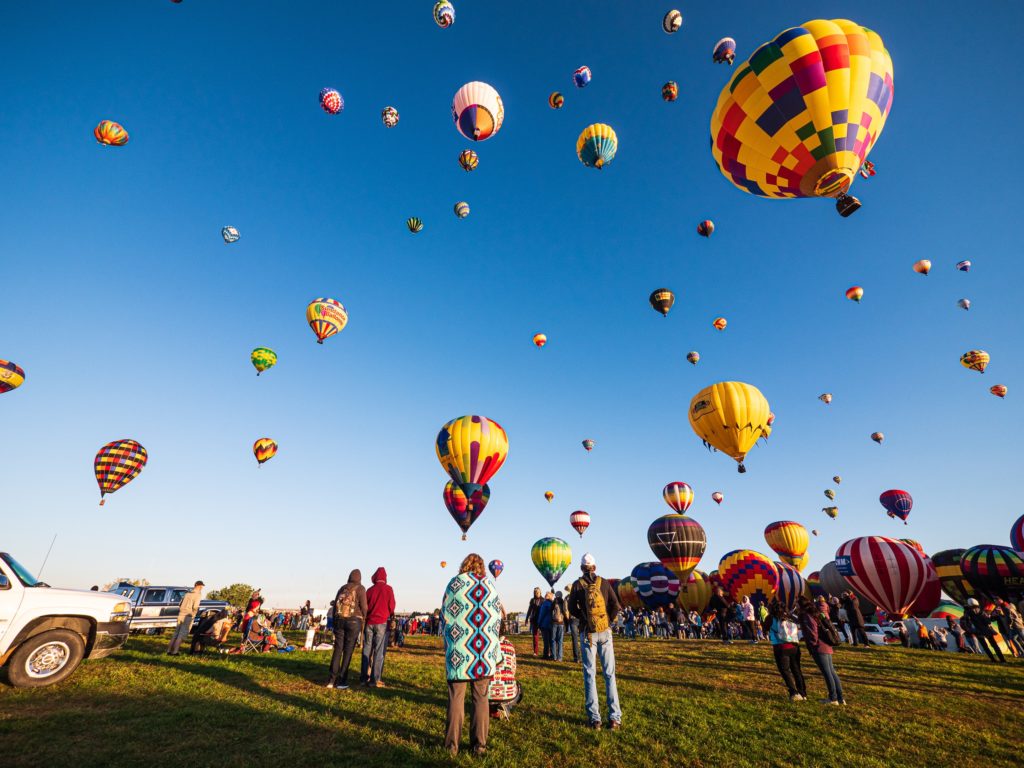 This image of the albuquerque international balloon fiesta with dozens of hot air balloons in fun shapes is featured in the Students fare travel blog tour guide "Best spots for Ballooning"