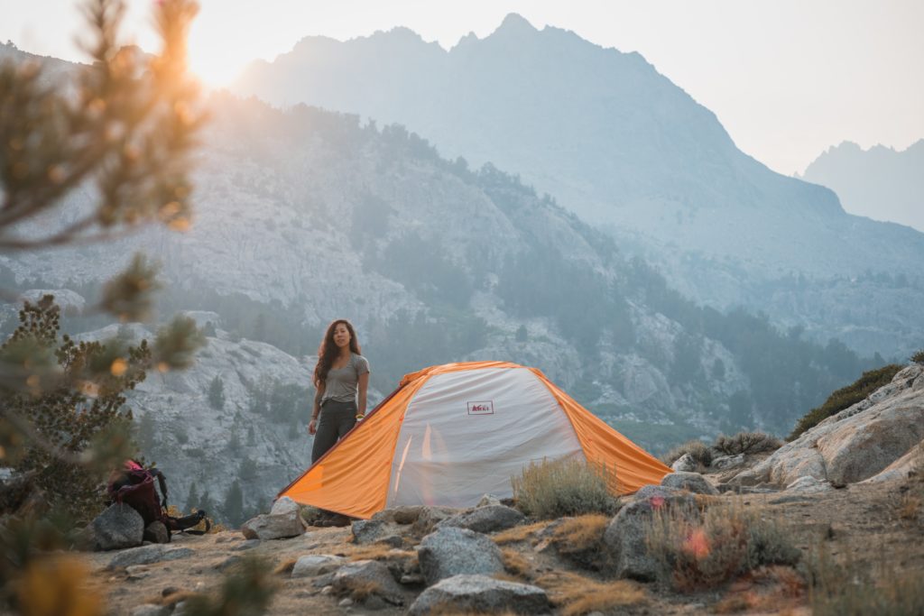Featured in the Backpacking Guide for Students by Students Fare, this image shows a woman camping in a tent.