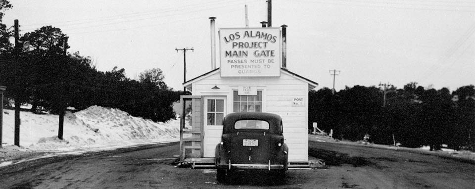 Featured in Oppenheimer Film Locations by Students Fare this historical image shows what the los alamos security gate looked like at the time of oppenheimer.