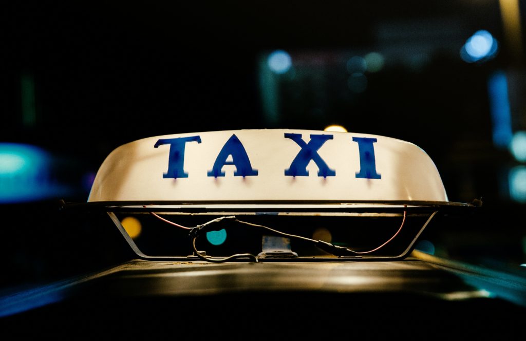 Featured in Tourist Scams to Avoid by Students Fare, this image shows the top of a taxi cab highlighted in light.