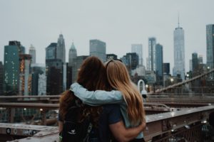 featured as the main image in the students fare blog post best destinations for young travelers this image shows two friends hugging in front of a city skyline