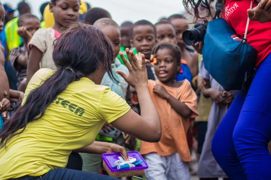 Featured in What Is A Volunteer Trip by Students Fare, this image shows a young student teacher surrounded by underprivileged kids.