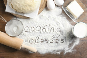 The featured image of Students Fare blog post "Best Culinary Tours for Students" which shows Text written on flour and ingredients, wooden background. Cooking classes concept