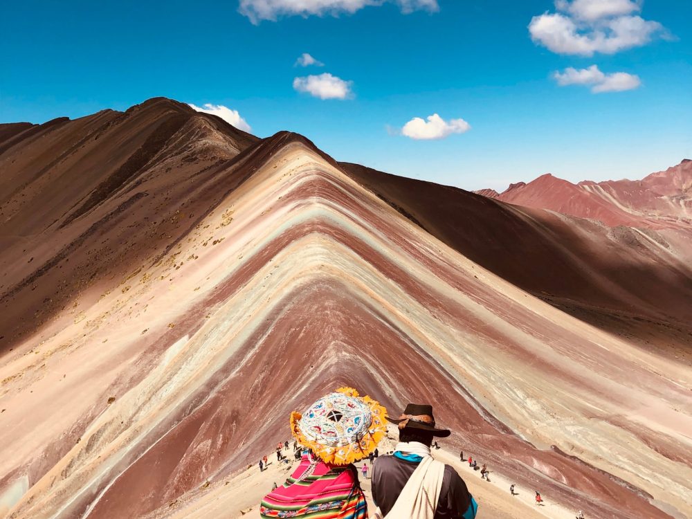 Two student travelers in traditional clothes take a tour of the Rainbow Mountain, named Vinicunca, part of the Andes of Peru.